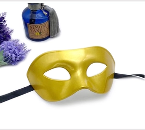 Detail of a vintage golden masquerade mask for men with black ribbons on white background