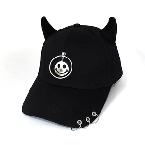 Detailed view of black devil horn baseball cap with metal rings and silver smiley face pendant