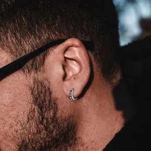 Nahaufnahme der Retro-Silber-Ohrring mit Totenkopf und Vintage-Textur am Ohr