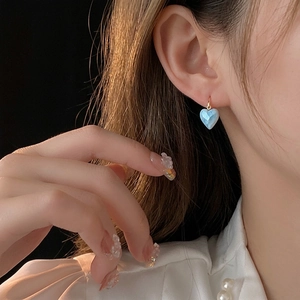 Boucles d'oreilles cœur bleu clair plaquées or portées pour un look élégant