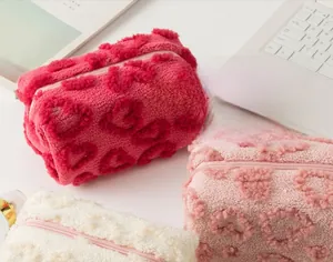 Macro shot of plush makeup bags with heart texture in pink, rose, and cream colors