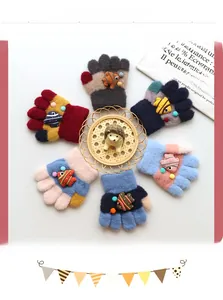 Flat lay of colorful thick knit children's gloves with cartoon fish and pom-pom details