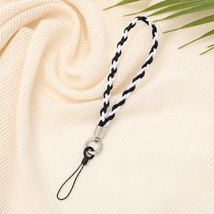 Minimalist black and white braided phone strap with silver ring on beige fabric