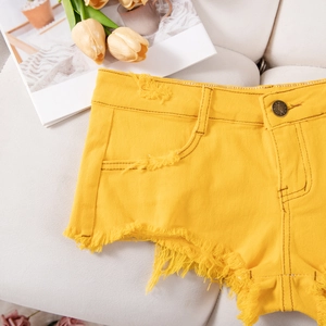Vista dettagliata degli shorts in denim giallo con bordi sfrangiati e bottoni decorativi