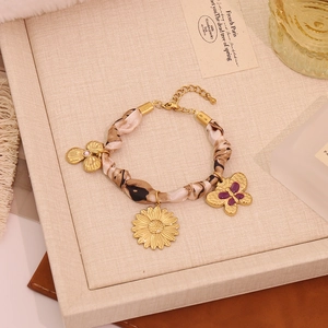 Detail of leopard print silk scarf bracelet with gold clover and purple butterfly charms