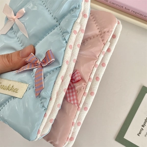 Close-up of quilted waterproof passport covers in pink and blue with bow details