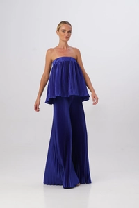Dettaglio del completo blu a pieghe con top a fascia e pantaloni larghi effetto lucido