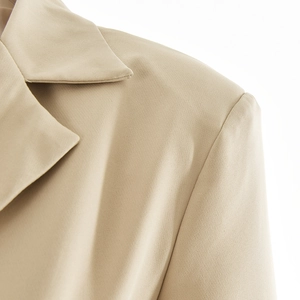 Close-up detail of khaki long sleeve cardigan shoulder and neckline texture