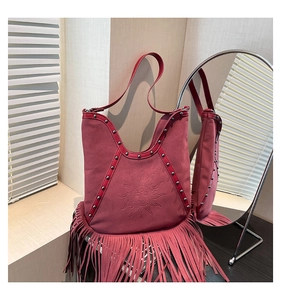 Detail of dark pink suede fringe bag with sun embossing and metal studs decor