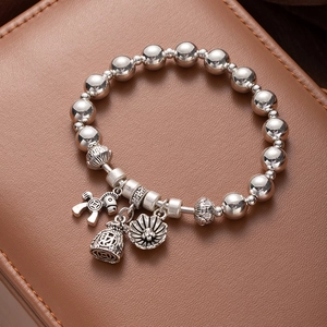 Detail of silver beaded bracelet with fortune bag and horse charms on brown leather