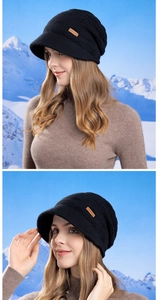 Detail of a black knitted bucket hat with a brown leather tag on a snowy mountain background