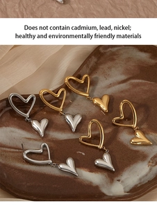 Close-up of heart dangle earrings in gold and silver finish on ceramic tray