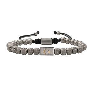 Detail of beaded bracelet showing moon and star rectangle charm and silver-grey beads