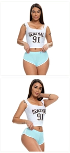 Detail von weißem Crop Top mit 'ORIGINAL 91' Print und blauen Sportshorts am Modell