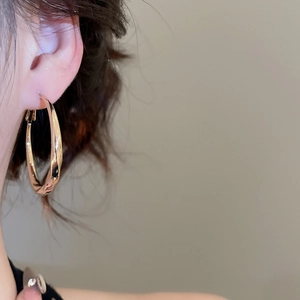 Close-up of elegant gold twisted hoop earring worn by a model for a stylish look