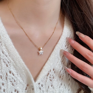 Close-up of gold-plated necklace with elegant double star pendants on woman's neck