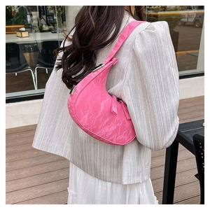 Detail of bright pink crinkled patent leather crescent shoulder bag with metal buckle