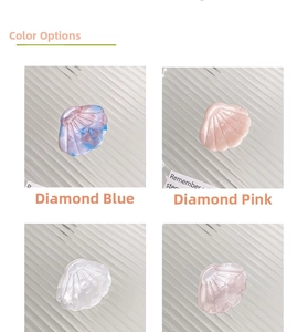 Detail view of shell-shaped acetate hair clips in four gradient colors on a glass tray