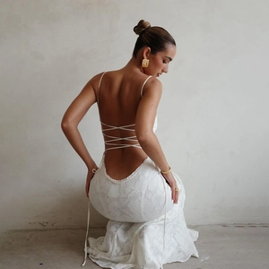 Détail d'une robe longue blanche dos nu avec fines bretelles et laçage croisé au dos