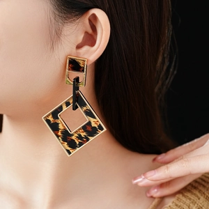 Detail view of large geometric leopard print earrings with gold metal diamond frames