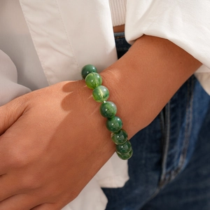 Close-up of a model wearing a green round acrylic beaded bracelet in a lifestyle setting
