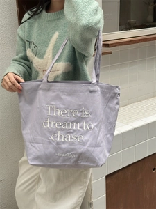 Detail of lavender canvas tote with embroidered white typography and durable texture