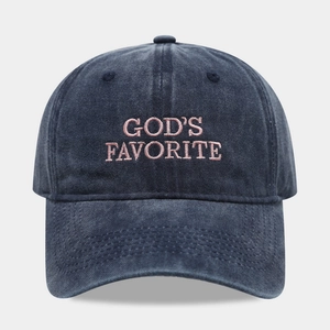 Close-up of pink 'GOD'S FAVORITE' embroidery on a washed navy cotton baseball cap