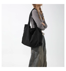 Side view of large black corduroy tote bag on model showing minimalist texture and size