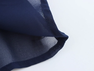 Detailed close-up of pleated navy blue chiffon fabric with professional edge stitching