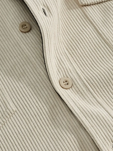 Macro detail of beige corduroy fabric texture and round buttons on casual shirt jacket