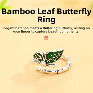 Macro detail of silver bamboo joint ring with green butterfly wing and floral enamel