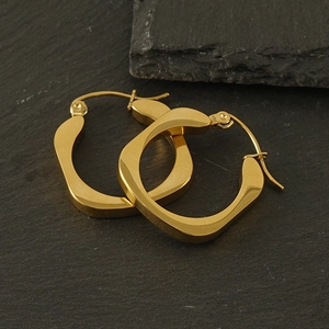 Macro view of geometric square gold-plated stainless steel earrings on stone surface