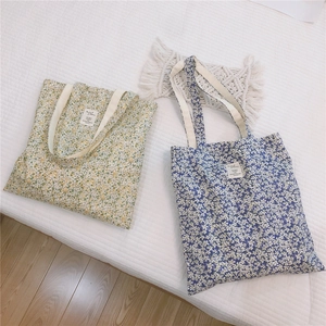 Close-up of floral cotton tote bags in yellow and blue colors on a white textured background