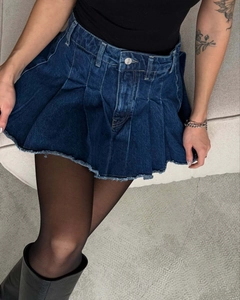 Dettaglio mini gonna a pieghe in denim blu scuro a vita alta con bordo in pizzo e bottone