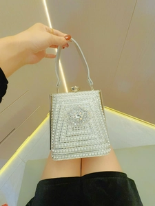 Detail of silver rhinestone evening clutch with sparkling floral clasp and top handle