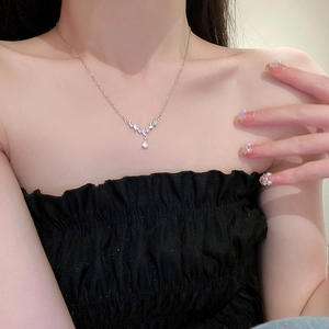Detail of V-shaped silver drop necklace with sparkling zircons worn by a model