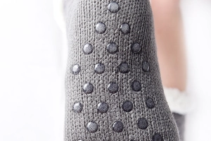 Detailed macro view of gray knit slipper socks featuring circular anti-slip grip bottom