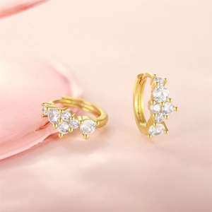 Macro shot of gold hoop earrings with claw-set cubic zirconia on silk background