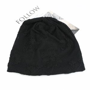 Close-up of black lace slouchy beanie with floral embroidery on white background