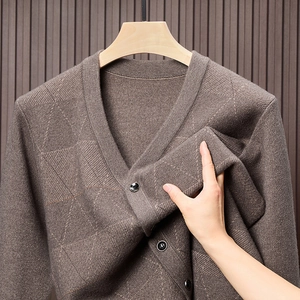 Detailansicht des weichen braunen Strickstoffs mit Rautenmuster und dunklen Knöpfen