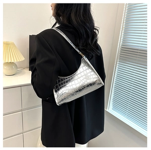 Detail view of silver crocodile pattern hobo bag worn on shoulder by female model