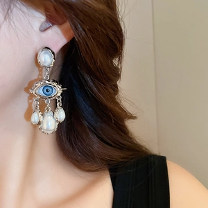Macro detail of retro evil eye earrings with silver metal and white pearl drops