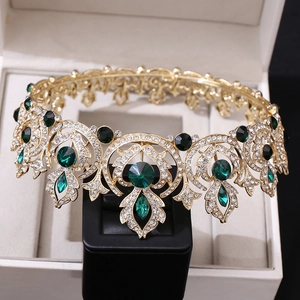 Macro shot of vintage gold crown with green gems and diamonds on a display stand