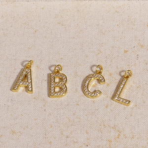 Macro shot of gold-plated letter A B C L charms inlaid with clear cubic zirconia stones