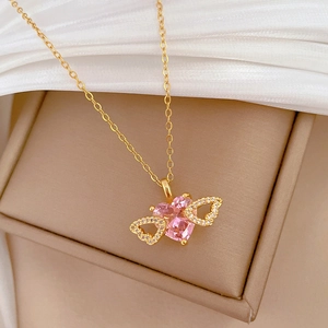 Close-up of golden wing necklace with sparkling pink heart gemstone on silk