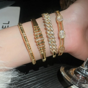 Detailed close-up of 18k gold plated bangle set with cubic zirconia on female wrist