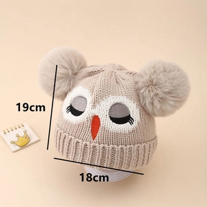 Détail du bonnet tricoté chouette pour bébé avec pompons, mesurant 19cm sur 18cm