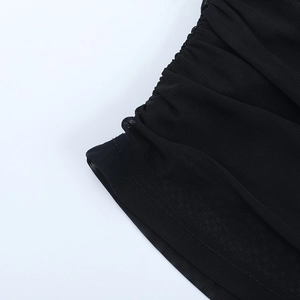 Détail du tissu en maille noire montrant le design froncé et la finition de couture