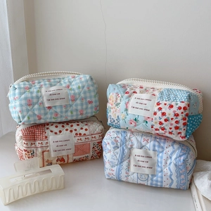 Detailed stack of quilted floral and checkered cotton cosmetic bags with zippers