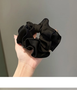 Close-up of a large black fabric scrunchie with sparkling rhinestone edging detail